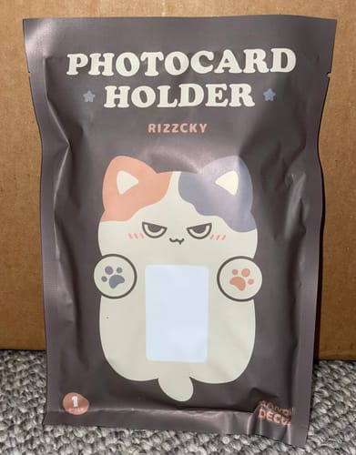 Customer shows the packaging for the RIZZCKY PHOTOCARD HOLDER, which features a cute cat graphic.