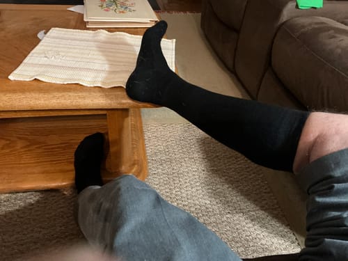 Reviewer resting with their leg on a coffee table while wearing black Performance Eucalyptus Compression Socks.