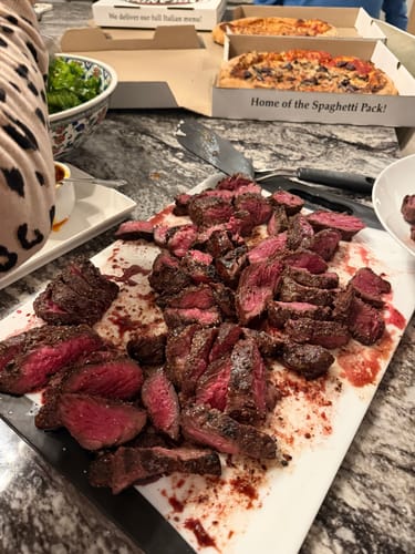 Customer's sliced Choice Hanger Steak on a cutting board, showing a rare, red center.