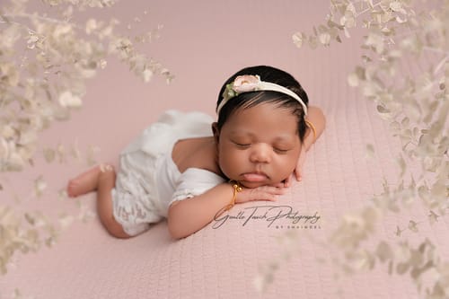 Reviewer's photo of a sleeping newborn framed with delicate white Botanical Branch Overlays on a pink background.
