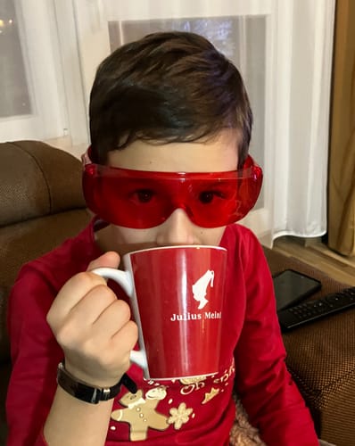 Customer wearing the red Complex VisionX glasses indoors while drinking from a mug.