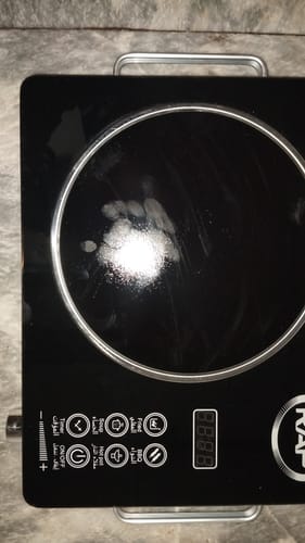 Reviewer's top-down view of the black RAF Infrared Electric Stove, showing the shiny cooktop and control panel.