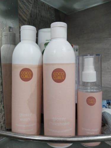 Customer's Glossy Hair Growth Bundle, showing the wash, milkshake, and magic drops bottles on a bathroom shelf.