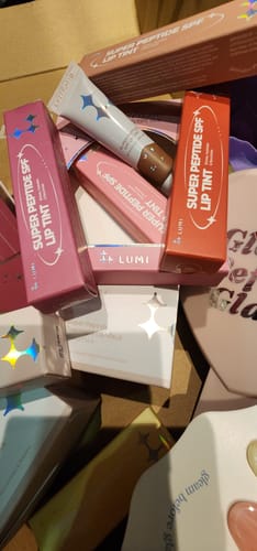 Close-up of a customer's Holiday Hues Bundle, showing colorful lip tint boxes and a tube inside a shipping box.