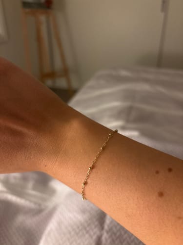 Reviewer showing their delicate gold Sparked by FinerRings bracelet on their wrist.