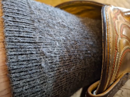 Customer's close-up of their grey Alpaca Socks slid down inside a boot.