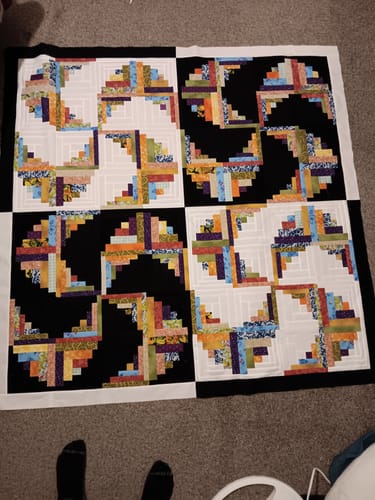 Customer's quilt top made with the Rainbow Swirls Quilt Pattern, showing colorful swirls on black and white blocks.