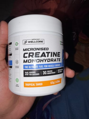 Customer holding a white tub of Wellcore Micronised Creatine Monohydrate in the Tropical Tango flavor.
