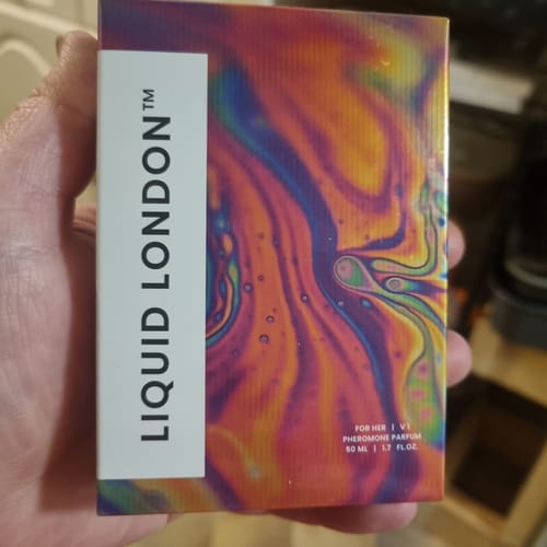 Customer holding the Liquid London For Her Pheromone Perfume box with its colorful, psychedelic design.