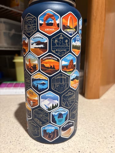 Reviewer's navy blue National Parks water bottle with colorful stickers applied over some of the engraved hexagon outlines.