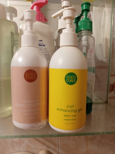 Customer's Leave-in Glossy Conditioner on a bathroom shelf next to another Coco Curls product.