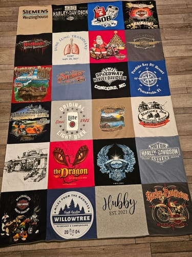 Customer's large Premium T Shirt Quilt made from personal shirts, including Harley-Davidson and 'Hubby,' spread on a floor.