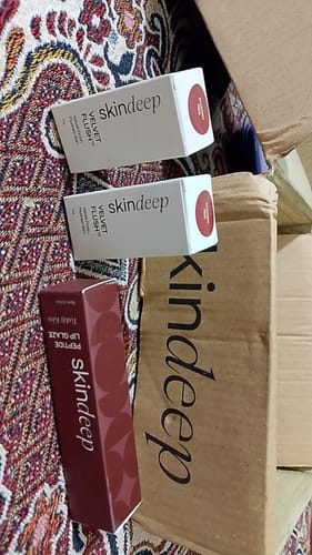 Reviewer's unboxing photo showing the packaging for the Peptide Lip Glaze and other Skindeep products.
