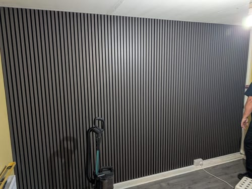 Reviewer's living room with a feature wall covered in dark grey Premium Acoustic Slatted Wall Panels.