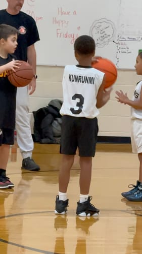 Customer's child wearing the black Joshua 1:9 Lion Performance Shorts on a basketball court.