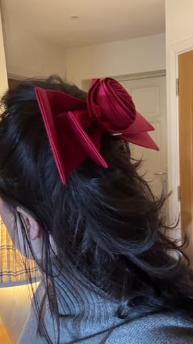 Reviewer wearing the large, red Tuscan Sun silk bow clip in their dark hair.