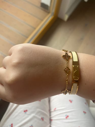 Eine Kundin trägt den goldenen Amore Zirconia Armreif mit weißen Akzenten am Handgelenk.