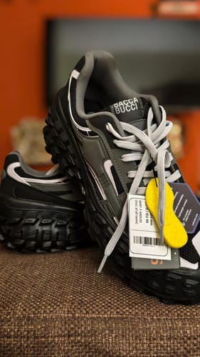 Reviewer's grey-black COLOSSUS shoes, showing the chunky all-terrain sole and attached yellow OrthoLite insole tag.