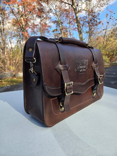 Reviewer's finished No.60 Western Leather Laptop Bag, crafted in a rich dark brown leather and placed on a surface outdoors.