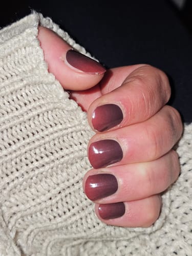 Nahaufnahme der Hand einer Kundin, die die glänzenden 'Just A Bite'-Nagelfolien mit einem rot-schwarzen Ombré-Effekt trägt.