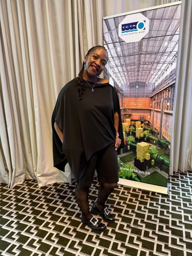 Reviewer at an event wearing the black loose one-shoulder blouse, showing its asymmetric design.