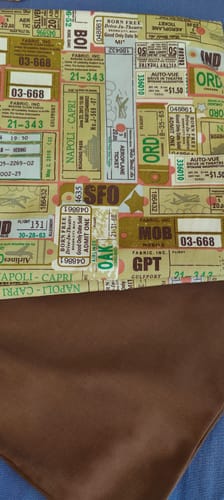 Customer's Travel Tickets Cotton Fabric laid out next to a piece of solid brown lining fabric.