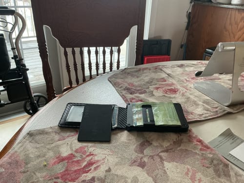 Customer's SPOTMINDERS Tracking Card placed inside an open black wallet on a table.