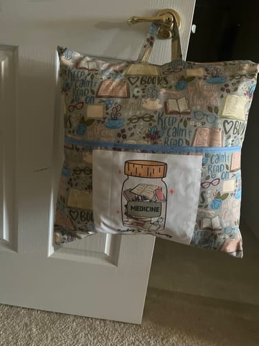 Customer's 'Reading Is My Therapy' fabric panel sewn onto a finished book-themed reading pillow, hanging on a door.