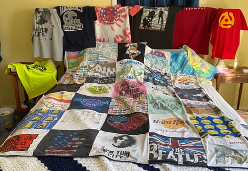 Customer's large, colorful Premium T Shirt Quilt made from various t-shirts spread across a bed.