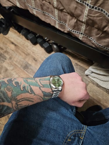 Customer wearing the silver Lucky Fours® Santos watch with a green dial on their tattooed arm.