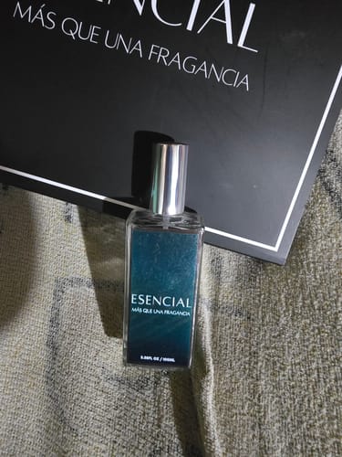 El cliente muestra el frasco del perfume H444 de Esencial, con su tapa plateada y empaque negro.
