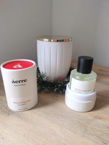 Customer's Springtime Muse perfume bottle and its packaging displayed on a wooden table next to festive decor.