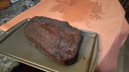 Customer's smoked USDA Prime Brisket with a dark bark resting on a metal baking sheet after cooking.