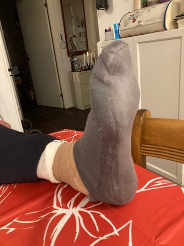 Kundens grå Diasocks ankelstrumpa buren över ett lindat ben för att visa passformen.