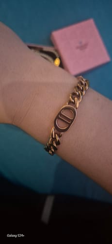 Kunde trägt ein goldenes Kettenarmband am Handgelenk, mit der rosa Geschenk Schatulle im Hintergrund.