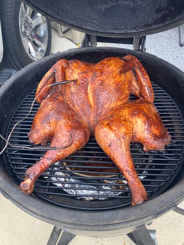 Customer's golden-brown turkey seasoned with Dirty Bird Rub cooking on a round smoker grill.