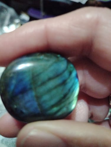 Close-up: Reviewer holding a polished labradorite crystal with a blue and green iridescent sheen.