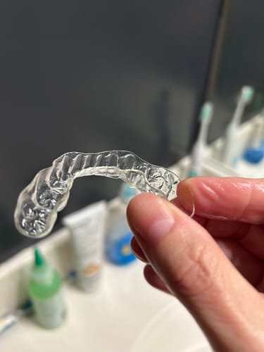 Customer holding the same retainer, now looking clean and clear after using the Dental Pod.