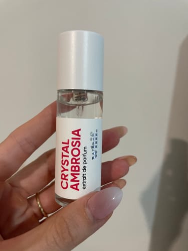 A customer's hand holding the small glass bottle of Crystal Ambrosia extrait de parfum.