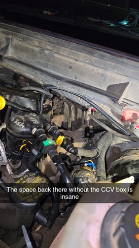 Reviewer shows the cleared space in an engine bay after installing the Powerstroke CCV Reroute Kit.