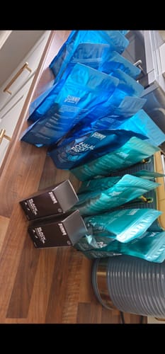 Customer's large supply of Halal Collagen Protein bags and boxes arranged on a wooden countertop.