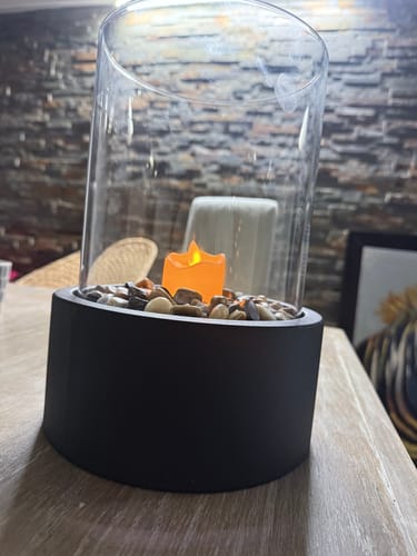 La chimenea de mesa de un cliente con una vela de baterías en lugar de la llama, sobre una mesa de madera.