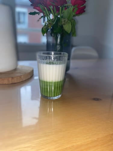 Photo d'un client : un verre de matcha latte bicolore préparé avec le THÉ MATCHA CÉRÉMONIE BIO, sur une table.