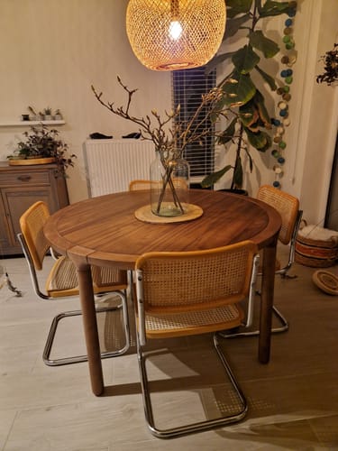 Recensent toont de ronde, donkerbruine Zuiver Storm eettafel in een sfeervol ingerichte eetkamer.