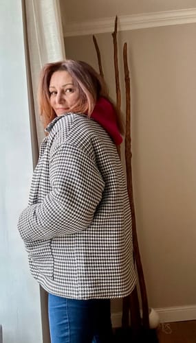 Cliente portant le Manteau Kaï pied de poule noir de manière ample sur une cagoule framboise.