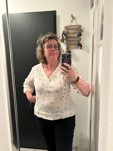 Cliente portant la blouse Eulalie florale en gaze de coton dans un selfie miroir.