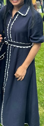 Customer wearing the navy Shyla Dress, showing the white scalloped trim on the collar, front, and tie waist belt.