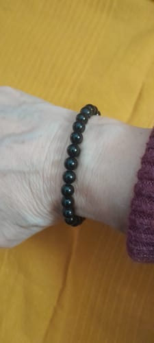 Un client portant le bracelet en Tourmaline noire à son poignet sur un fond jaune.