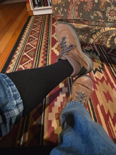 A customer's leg shown wearing a black Performance Eucalyptus Compression Sock with a brown boot.