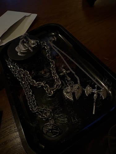 Customer's collection of silver Zodiac Pendants and chains laid out in a black tray.
